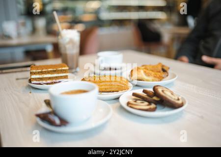 Zwei Tassen Cappuccino mit verschiedenen Kuchen und Gebäck auf einem Holztisch. Kaffee am Morgen im Café im Freien. Stockfoto