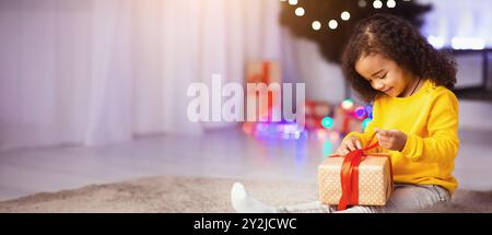 Cute afrikanischen kid Eröffnung Weihnachtsgeschenk zu Hause Stockfoto