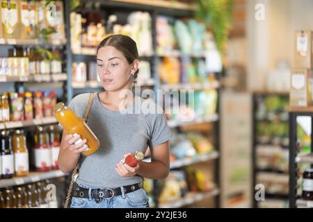 Interessiertes Mädchen, das über die Auswahl von Bio-Saft im Naturkostladen nachdenkt Stockfoto