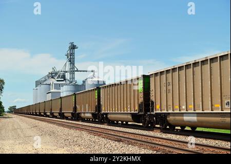 Meriden, Illinois, USA. Ein leerer Burlington Northern Santa Fe Kohlezug, der einen Getreideaufzug im ländlichen Illinois überquert. Stockfoto