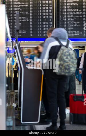 Eine Reihe von Reisenden wartet an einem Selbstbedienungskiosk am Flughafen auf den Check-in und die Gepäckabgabe. Das Flughafenterminal ist voll mit Menschen und Gepäck, an Stockfoto