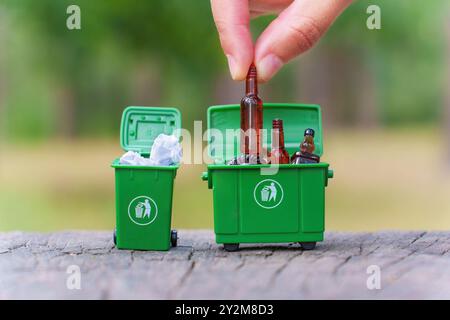 Grüne Minibehälter, die im Außenbereich mit Flaschen und Abfallmaterialien von Hand gefüllt werden. Stockfoto