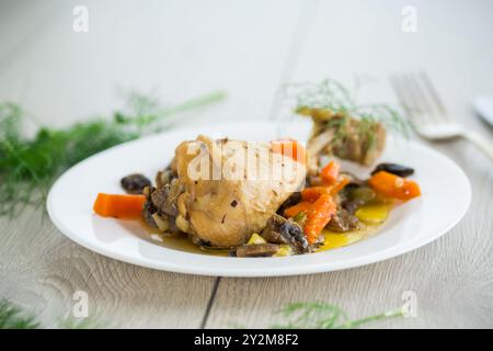 Hähnchenbraten mit Pilzen und Gemüse auf einem Teller auf einem Holztisch. Stockfoto