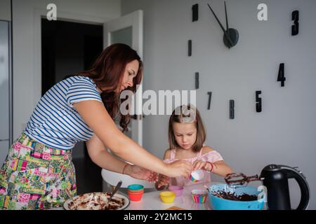 Mutter und Tochter backen zusammen Cupcakes in der Küche Stockfoto