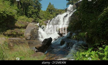 Heiterer Wasserfall, der über Felsen im tropischen Wald stürzt, lebendig Stockfoto