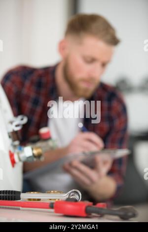 Klempner schreiben in Zwischenablage und prüfen Elektrokessel Stockfoto