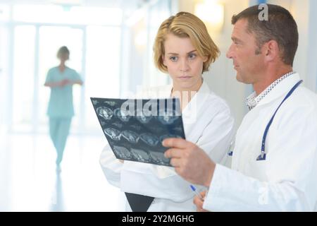 Ärzte diskutieren Patientenröntgen auf Korridor Stockfoto