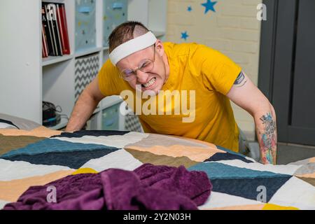 Eine entschlossene Person, die Liegestütze drinnen in einem gemütlichen Raum macht und sich auf das Fitnesstraining konzentriert, während sie legere Trainingsanzüge trägt. Stockfoto