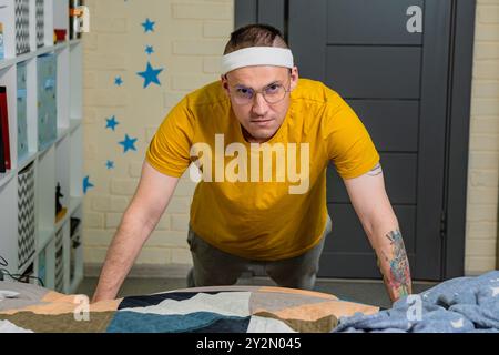 Eine entschlossene Person, die Liegestütze drinnen in einem gemütlichen Raum macht und sich auf das Fitnesstraining konzentriert, während sie legere Trainingsanzüge trägt. Stockfoto