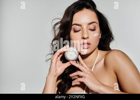 Eine junge Frau zeigt ihre Hautpflegeroutine auf einem farbenfrohen Hintergrund. Stockfoto