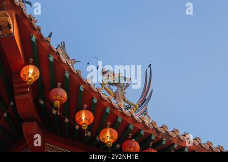 Lebendige chinesische Drachenskulptur auf dem Tempeldach mit roten Laternen. Stockfoto