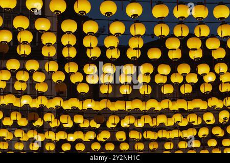 String of Yellow Laternen: Eine Nahaufnahme einer Reihe leuchtender gelber Laternen, die über ihnen hängen und eine festliche Atmosphäre schaffen. Stockfoto