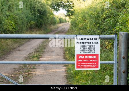 Ein Farmwatch Protected Area Schild an einem Tor gegenüber einer Farmstraße in Norfolk. Stockfoto