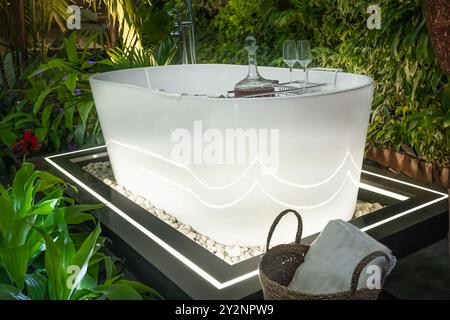 Moderne weiße Badewanne im Garten. Wannen-Whirlpool in romantischer Natur. Idyllische Badewanne im Freien. Außenterrasse eines luxuriösen Privathauses mit heißem tu Stockfoto