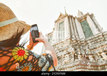 Nahaufnahme weiblicher Tourist, der Fotos mit dem Handy am wunderschönen Wat Arun Tempel in Bangkok, Thailand macht. Autor von Inhalten für berühmte Touristenziele c Stockfoto