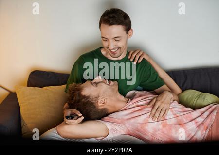 Zwei Männer teilen freudige Momente auf der Couch, umarmen und lachen zusammen. Stockfoto