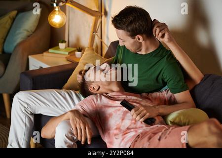 Zwei Männer teilen sich einen freudigen Moment, während sie sich auf ihrer Couch entspannen. Stockfoto