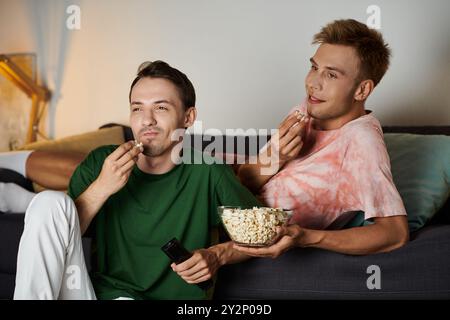 Ein fröhliches Paar genießt Popcorn, während es sich auf der Couch entspannt. Stockfoto