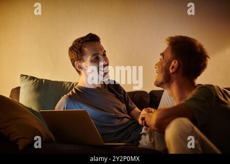 Zwei Männer teilen freudige Momente, während sie sich in ihrem Wohnzimmer entspannen. Stockfoto