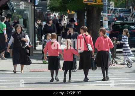 Eine Straßenszene mit 4 bescheiden gekleideten Schwestern mit derselben Kleidung und Frisur. Auf der Lee Avenue in Williamsburg, Brooklyn, New York. Stockfoto