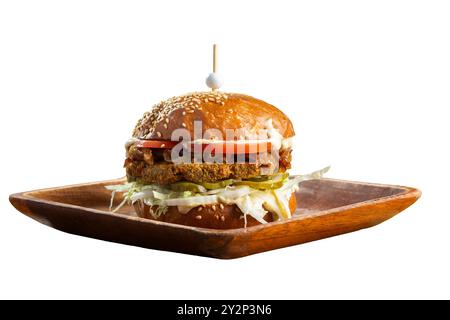 Großer leckerer Burger mit gebratenem Kotelett, Kohlsalat, Tomaten und Sauce auf Holzteller isoliert auf weißem Hintergrund. Stockfoto