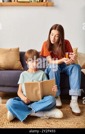 Eine Mutter verlockt ihren Sohn mit dem Lesen, während sie ein warmes Getränk genießt. Stockfoto