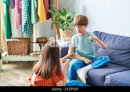 Die Mutter spielt spielerisch mit ihrem hörgeschädigten Sohn in einem gemütlichen Wohnzimmer. Stockfoto