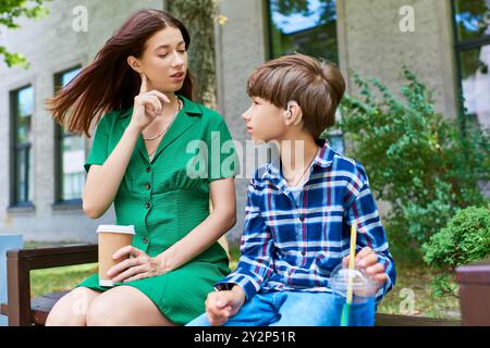 Eine Mutter engagiert sich liebevoll mit ihrem hörgeschädigten Sohn in einem ruhigen Park. Stockfoto