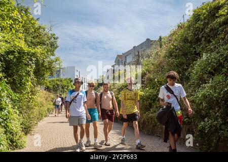 Eine Gruppe junger männlicher Urlauber, die entlang der Tram Tram Tram Tracks im Stadtzentrum von Newquay in Cornwall in Großbritannien spazieren. Stockfoto