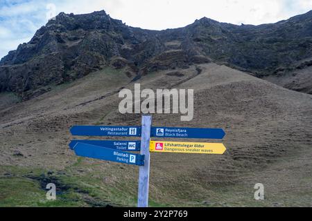 Vik, Island - 6. Mai 2024: Ein verwittertes hölzernes Straßenschild weist auf Reynisfjara, Islands berühmten schwarzen Sandstrand. Diese einsame Ikone ist eingebettet zwischen d Stockfoto