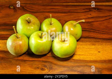 Sechs grüne Äpfel sitzen auf einem Holztisch Stockfoto