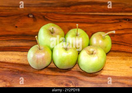 Sechs grüne Äpfel sitzen auf einem Holztisch Stockfoto