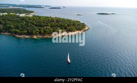 Porec, Istrien, Kroatien - 26. August 2024: Luftaufnahme einer Küstenlandschaft in Kroatien mit einem einsamen Segelboot, das ruhig auf dem Adriatischen Meer segelt *** Luftaufnahme einer Küstenlandschaft in Kroatien mit einem einsamen Segelboot, das ruhig auf dem Adriatischen Meer segelt Stockfoto