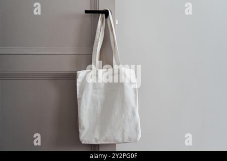 Weiße umweltfreundliche Tasche, die am Türgriff hängt. Tragetasche aus Segeltuch Stockfoto