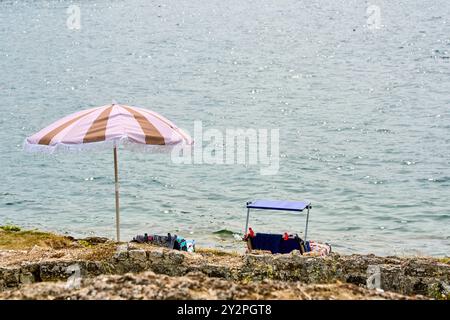 Porec, Istrien, Kroatien - 26. August 2024: Ein idyllischer Badeplatz mit Sonnenschirm und Liegestühlen an der felsigen Küste der Adria in Kroatien *** ein idyllischer Badeplatz mit Sonnenschirm und liegen an der felsigen Küste der Adria in Kroatien Stockfoto