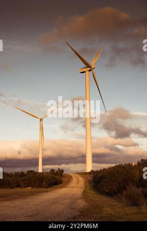 Zwei Windmühlen Turbinen auf einem Berg bei Sonnenuntergang, goldene Stunde. Konzept der erneuerbaren Energien Stockfoto