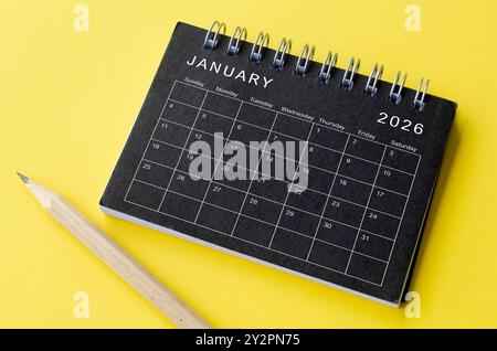 Draufsicht des Kalenders Januar 2026 auf schwarzem Notizblock mit gelbem Hintergrund. Neujahr- und Kalenderkonzept. Stockfoto