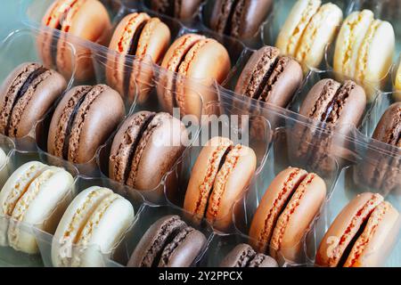 Tischansicht eines Pakets mit verschiedenen aromatisierten französischen Macarons. Weiße, Milch- und Zartbitterschokolade mit Orangenaromen. Stockfoto