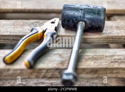 Gebrauchte Werkzeuge , Gummihammer und Zange auf Holzdielen Stockfoto