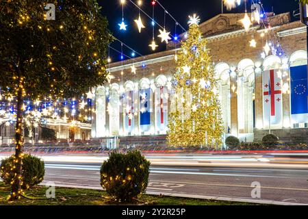 Festliche Weihnachtslichter umgeben die Architektur in Tiflis, Georgien, mit einem großen Baum und glitzernden Sternen. Stockfoto