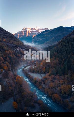 Panoramablick auf die aragonesischen Pyrenäen im Herbst, mit dem lebendigen Laub, das den kurvenreichen Pfad des Flusses Ara mit majestätischen Bergen umgibt Stockfoto
