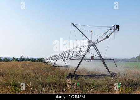 Ein großes Pivot-Bewässerungssystem bewässert Maispflanzen in den Feldern von Castilla La Mancha, Spanien, und zeigt moderne landwirtschaftliche Praktiken in einem landschaftlich reizvollen rur Stockfoto