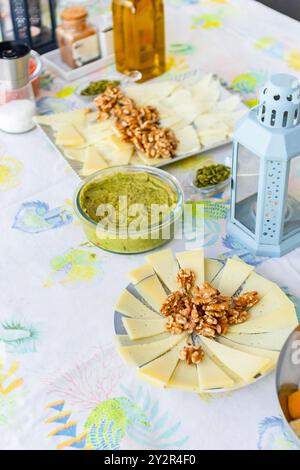 Eine verlockende Auswahl an verschiedenen veganen Snacks und Dips einschließlich Käsescheiben, Walnüssen und Guacamole auf einer farbenfrohen Tischdecke. Perfekt für einen Urlaub Stockfoto