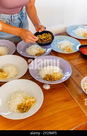 Die zugeschnittene unerkennbare Frau baut während eines kulinarischen Workshops in einem Retreat vegane Poke-Schüsseln zusammen und fügt Reis in bunten Schüsseln Sojabohnen hinzu. Das Fo Stockfoto