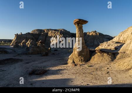 Die hoch aufragenden Sandsteinformationen und Hoodoos der Ah-Shi-SLE-PAH Wilderness stehen unter einem klaren Himmel, beleuchtet vom warmen Glanz der untergehenden Sonne Stockfoto