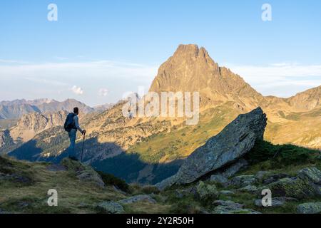 Rückansicht eines nicht erkennbaren Mannes, der durch die malerischen französischen Pyrenäen wandert und ihn von hinten zeigt, während er bei Sonnenaufgang auf einem zerklüfteten Pfad navigiert. Stockfoto