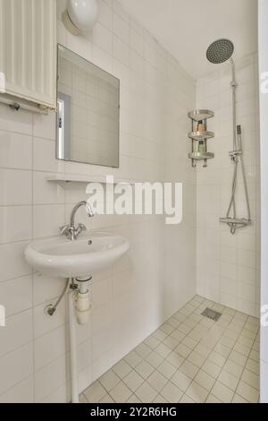 Ein kompaktes Badezimmer mit weißen Fliesen, Standwaschbecken, Dusche und Wandspiegel. Stockfoto