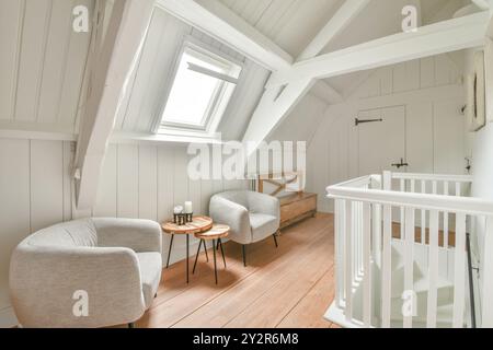 Helles und einladendes modernes Dachgeschoss mit komfortablen Sitzgelegenheiten, Holzboden und Dachfenster. Stockfoto