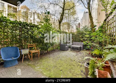 Ein einladender urbaner Garten im Hinterhof mit verschiedenen Sitzanordnungen, umgeben von üppigem Grün und privaten Hecken. Stockfoto