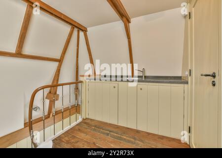 Gemütlicher Dachboden mit alten Holzbalken, eingebautem Schrank mit Waschbecken und Hartholzboden. Stockfoto